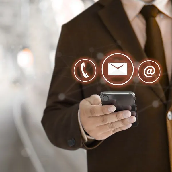 Mão segurando smartphone com ícones de telefone, e-mail e website, representando o suporte ao cliente da Vortex-R para chillers e reatores encamisados.