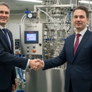 Dois empresários dando as mãos e fechando negócio com um reator da Vortex-R ao fundo em ambiente industrial